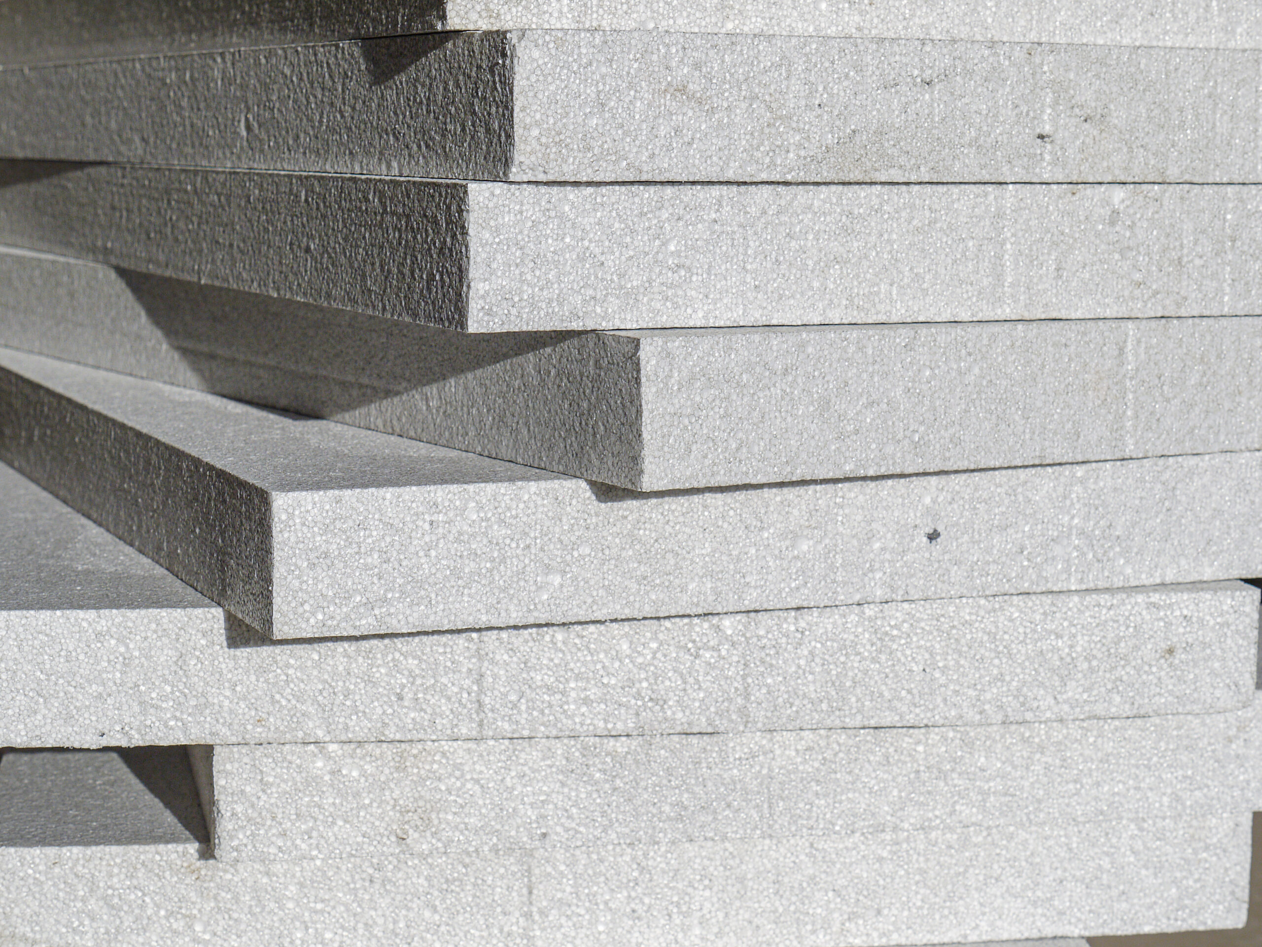 Stacked white polystyrene foam boards with rough textured surfaces, stacked in a pile for insulation