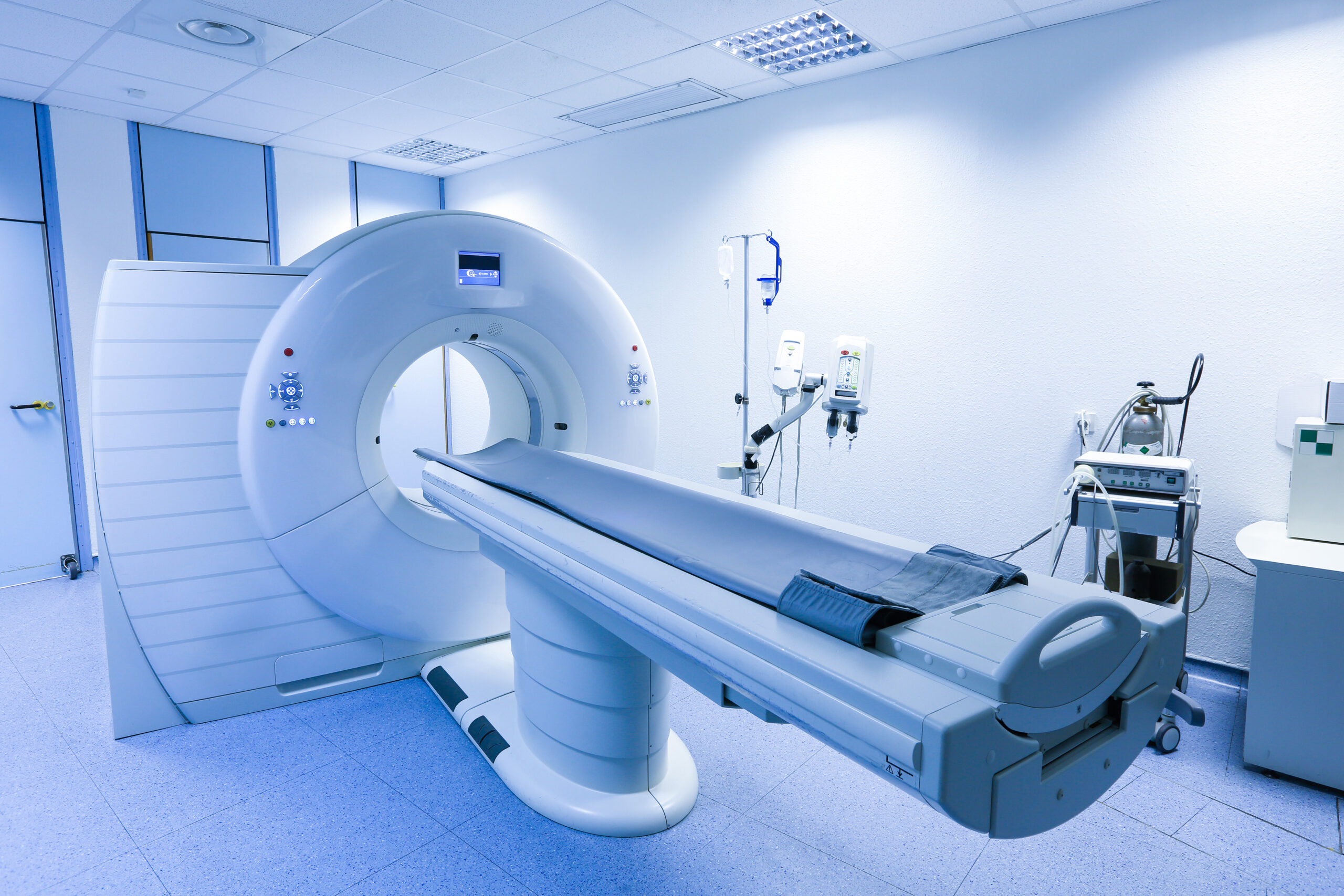 Mri scanner in a hospital radiology room with the patient table extending from the bore, ready for a scan.