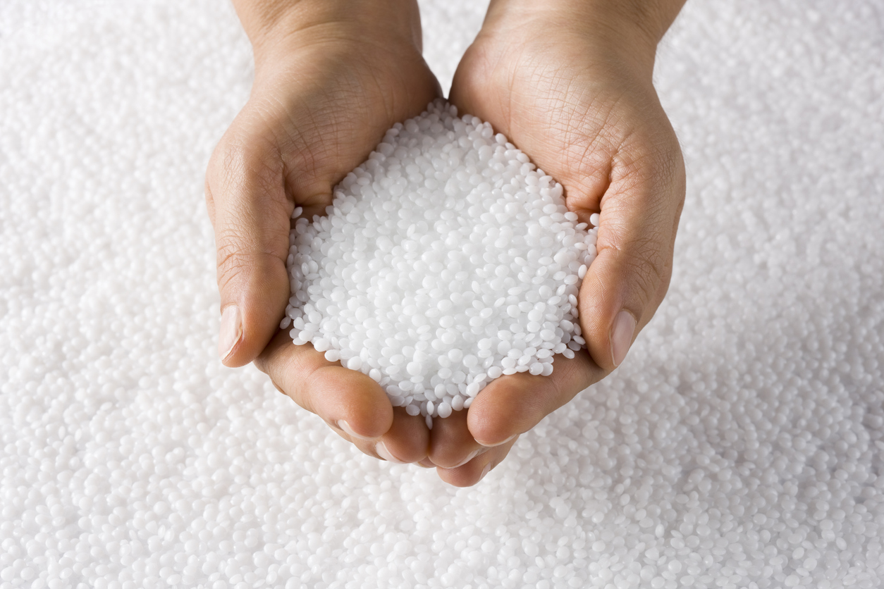 Plastic Resin Pellets | Reedy Chemical Foam Hands cupping small white plastic pellets over a bed of pellets in the background.