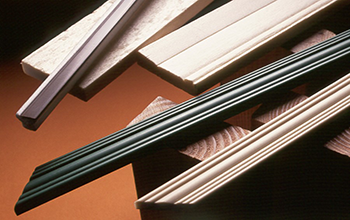 Foamprofiles | Reedy Chemical Foam Close-up of several wooden slats and a black ruler-like object arranged diagonally on an orange-brown background.