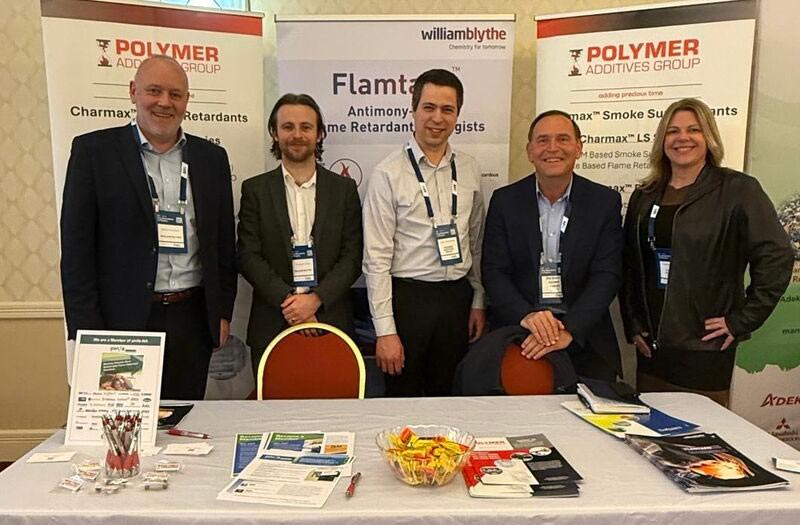 Pag employees stand together by their table at a convention.